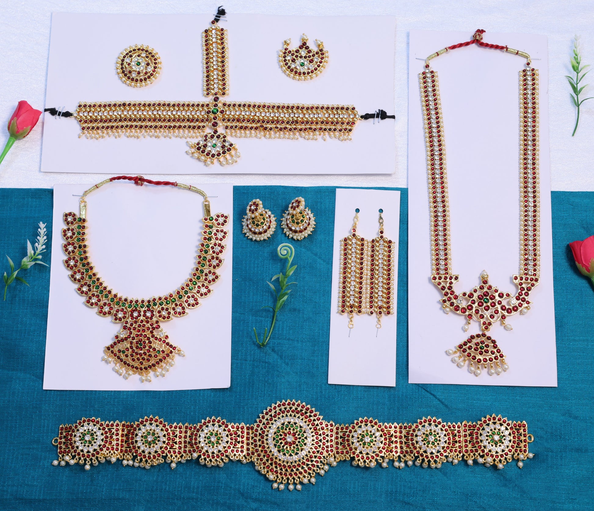 Full Arangetram Bharatanatyam temple jewellery set with Kemp stones, including haram, choker, jhumkas, vanki, oddiyanam, and headpiece arranged on a blue and white background.